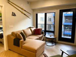 a living room with a couch and a table at Black Bears Den, Heated Pool, Hot Tub, AC, brand new unit! in Canmore +17 photos