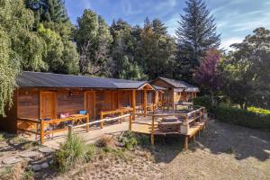 a wooden cabin with a deck in the woods at Las Carpitas in Villa Mascardi