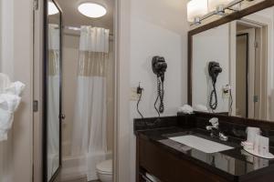 
a bathroom with a mirror, sink, and shower at Ramada by Wyndham Boston in Boston
