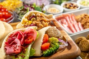a wooden cutting board with sandwiches and other foods at Hotel Mystays Premier Hamamatsucho in Tokyo