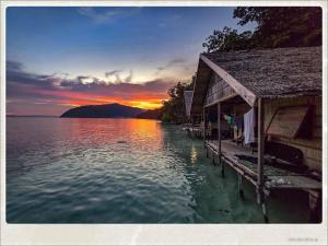 a sunset over the water next to a dock at Lumba Lumba Homestay in Kri