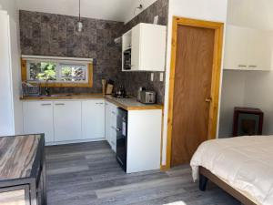 a kitchen with white cabinets and a bed in a room at Ruta Divisadero in Coihaique +4 photos