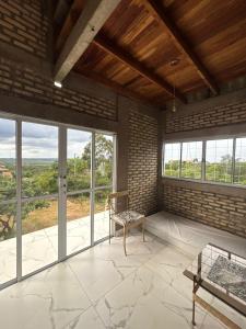 a living room with windows and a couch and a chair at Chalé Florada d' Serra in Chapada dos Guimarães