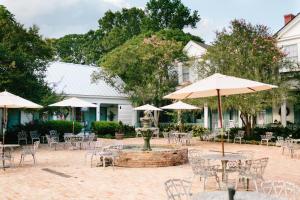 un patio esterno con tavoli, sedie e ombrelloni di The Myrtles a Saint Francisville