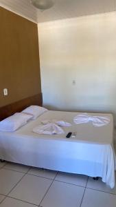 a bedroom with a white bed with a laptop on it at Pousada e Restaurante Coração De Mãe in Prado +2 photos
