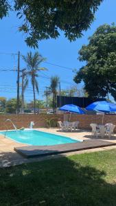 a swimming pool with chairs and umbrellas next to it at Pousada e Restaurante Coração De Mãe in Prado