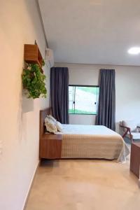 a bedroom with a bed and a window at Chalé Vertente da Canastra in São Roque de Minas