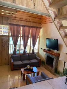 a living room with a couch and a tv at Cabañas El Ensueño in La Ciudad