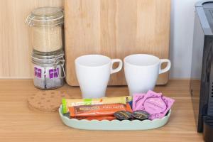 a plate of food and two cups on a table at Beckford Tiny House 2 by Tiny Away in Good Hope
