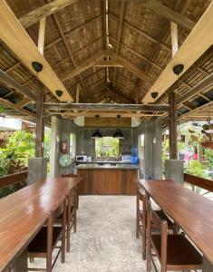 a dining room with wooden tables and a kitchen at Villa Peray Siargao in General Luna