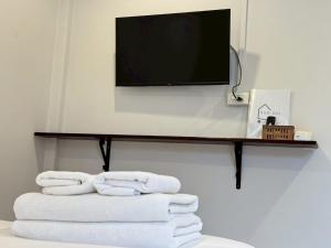 a shelf with towels and a television on a wall at บ้านสุดซอย-Baan Sud Soi in Prachuap Khiri Khan