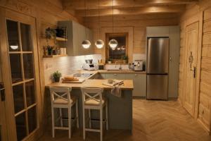 a kitchen with a refrigerator and a counter with stools at Domek w sam las in Ochotnica Dolna