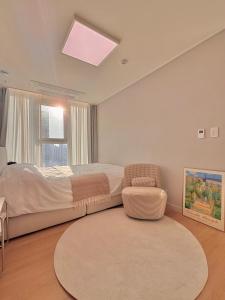 a bedroom with a bed and a chair and a rug at Azur Stay in Kwangan-dong