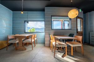 a dining room with two tables and chairs and windows at Oceanfront Up to 14 Guests BBQ Available オーシャンフロント小浜田烏 in Obama