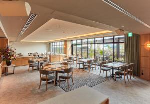 a restaurant with tables and chairs and windows at Hotel Terrasta in Miyakonojō