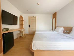 a bedroom with a large white bed and a desk at Wynora Hotel in Klong Toi