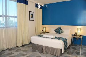 a bedroom with a large bed with a blue wall at Stacia Hotel in Cebu City