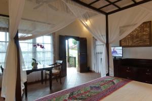 a bedroom with a bed and a table and a desk at Cempaka Belimbing Villa in Blimbing