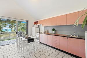 a kitchen with pink cabinets and a table at ParkView on Owen in Huskisson