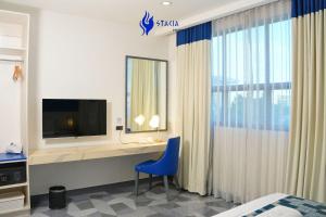 a bedroom with a desk with a tv and a blue chair at Stacia Hotel in Cebu City