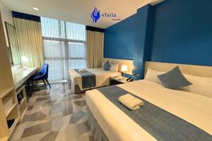 a hotel room with two beds and a desk at Stacia Hotel in Cebu City