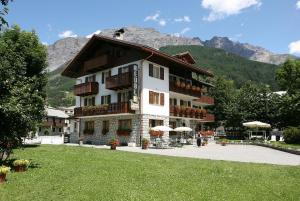 a large building with a mountain in the background at Meublè Cima Bianca Garni in Bormio