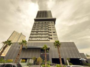 a tall building with palm trees in front of it at Sky Design Alphaville Hotel Residence in Barueri