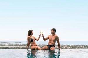 a man and woman sitting in the water with glasses of wine at Savaya Samui Villa in Ban Ko Khwan