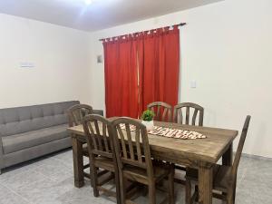 a dining room table with chairs and a red curtain at Cima Departamentos in Rivadavia