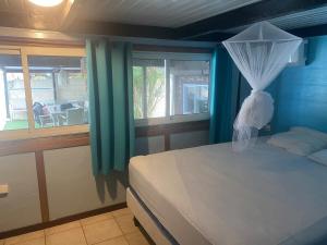 a bedroom with a bed with blue walls and a window at FARE MOOREA in Moorea +42 photos