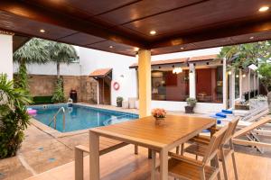 a patio with a wooden table and chairs next to a pool at Katanoi Resort in Kata Beach