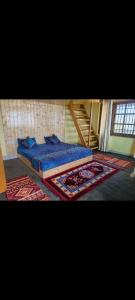 a bedroom with a bed with blue sheets and rugs at Shiva cottage in Kullu Manali