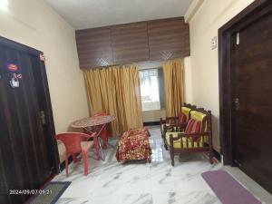 a room with chairs and a table and a door at Cozy braket in kolkata