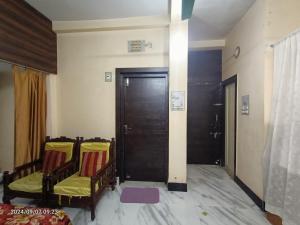a room with two chairs and a wooden door at Cozy braket in kolkata