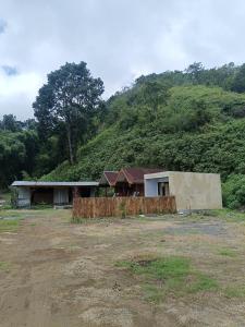 a house in a field next to a mountain at Queen Rinjani Stay & Café in Sembalun Lawang