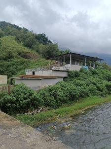 a building on top of a hill next to a river at Queen Rinjani Stay & Café in Sembalun Lawang