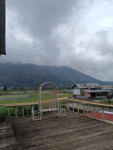 a bench sitting on a deck with a view of a mountain at Queen Rinjani Stay & Café in Sembalun Lawang +5 photos