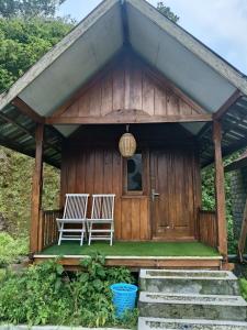 a wooden cabin with two white chairs on the porch at Queen Rinjani Stay & Café in Sembalun Lawang