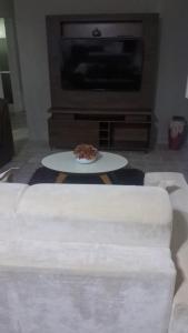 a living room with a white couch and a tv at Casa Samambaia in Piranhas