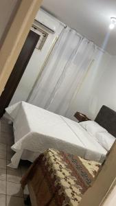 a bed with a white comforter in a room at Casa Samambaia in Piranhas