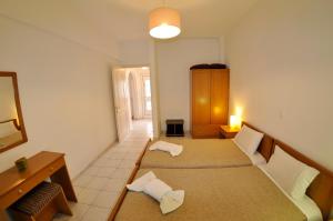 a room with two beds and a table and a mirror at Egli Apartments in Kontokali +22 photos