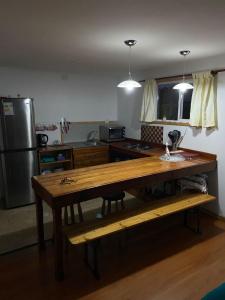 a kitchen with a wooden table and a refrigerator at Entre Pinos y Volcanes in Frutillar