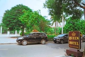 two cars parked in a parking lot with a queen hotel sign at Queen Hotel Van Phu Urban in Hà Ðông