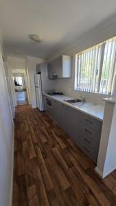 a kitchen with white cabinets and a wooden floor at Four Seasons Holiday Park in Marybrook
