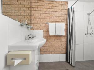 a bathroom with a white sink and a brick wall at Kennedy Drive Boutique Motel & Nursery- Close To City Centre & Airport - 24 Hour Self Check-In in Tweed Heads +94 photos
