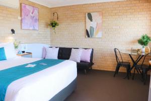 a hotel room with a bed and a table with a table at Kennedy Drive Boutique Motel & Nursery- Close To City Centre & Airport - 24 Hour Self Check-In in Tweed Heads