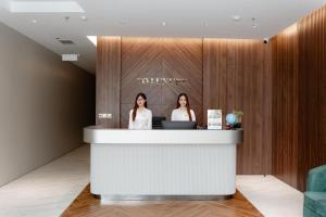 two women standing at a counter in a hotel lobby at TQ Luxury Hotel & Apartment in An Khê