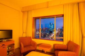 a room with two chairs and a window with a city skyline at Hotel Okura Niigata in Niigata