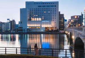 a woman standing next to a river in a city at Hotel Okura Niigata in Niigata