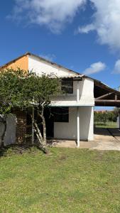 a white house with a tree in front of it at Los Rochas, Barra de Chuy in Barra del Chuy